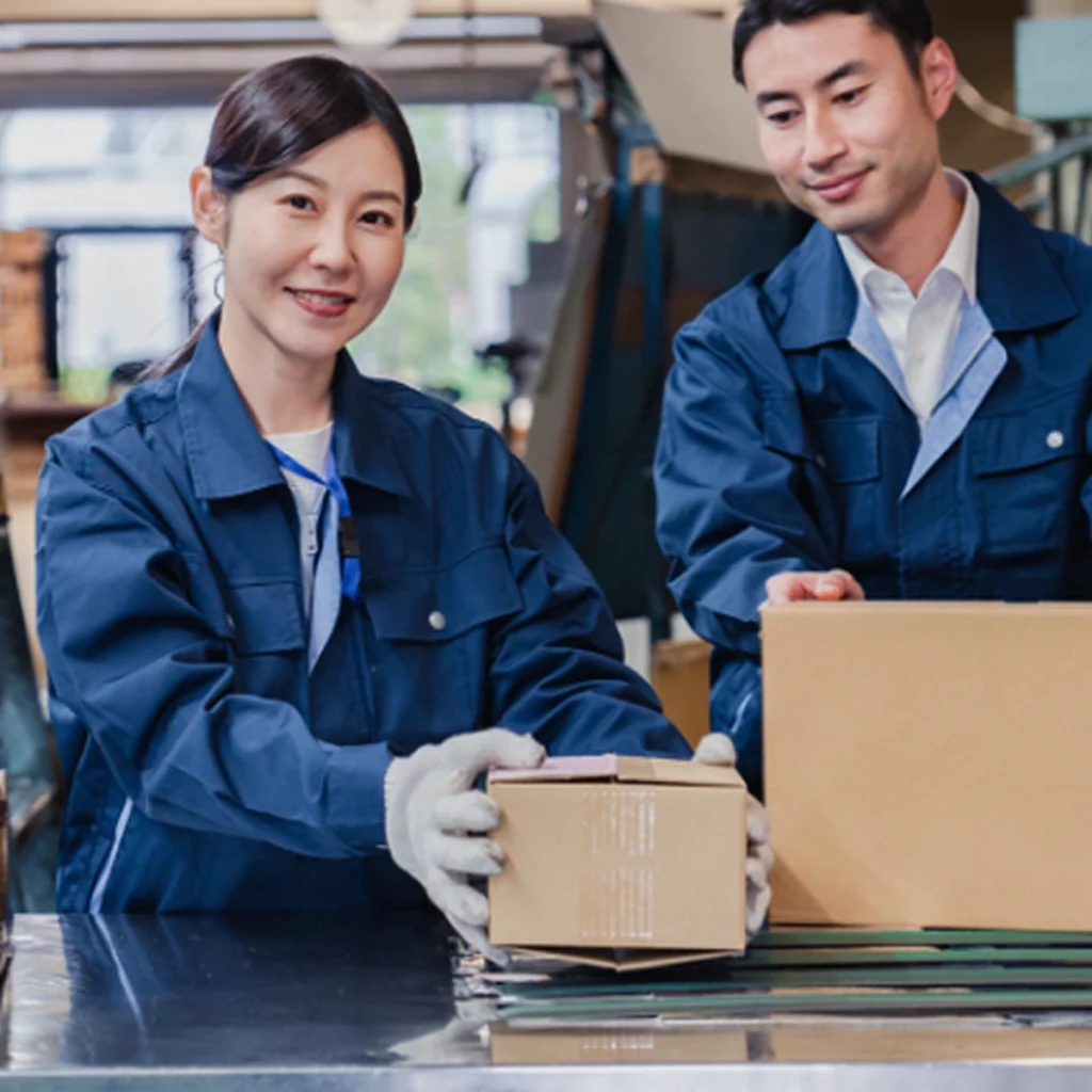 Two workers packaging boxes in a warehouse.