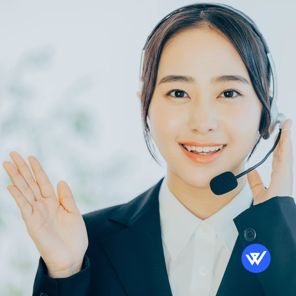 Professional Japanese customer support representative wearing a headset, smiling and waving, representing WeLink's customer support services.